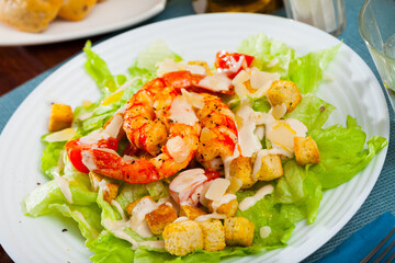 Delisiously Caesar salad with prawns, lettuce, sauce and cheese. High quality photo