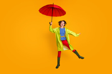 Full length photo portrait of elegant girl jumping up with open umbrella isolated on vivid yellow...
