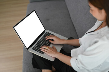 Cropped shot of a beautiful young woman in casual clothing using laptop while resting on sofa at home.