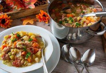 cabbage soup on a plate with pot served on a kitchen table with spoons