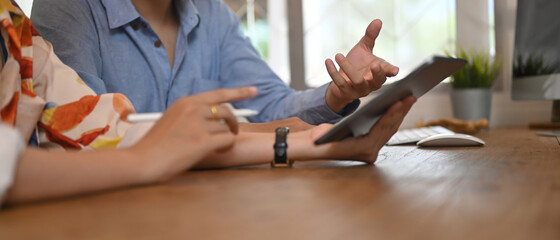 Cropped shot of business people discussing project in tablet at meeting room.