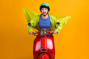 Photo portrait of excited girl riding bike forward isolated on vivid yellow colored background