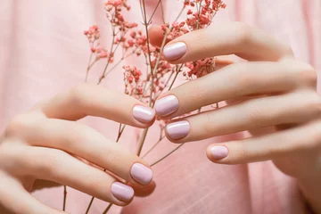 Wall murals Manicure Female hands with pink nail design. Pink nail polish manicure. Woman hands hold pink flowers.