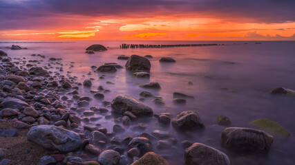 Rocky beach with stormy sea and dramatic sunset sky
