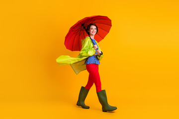 Full length photo portrait of smiling woman walking under umbrella isolated on bright yellow...