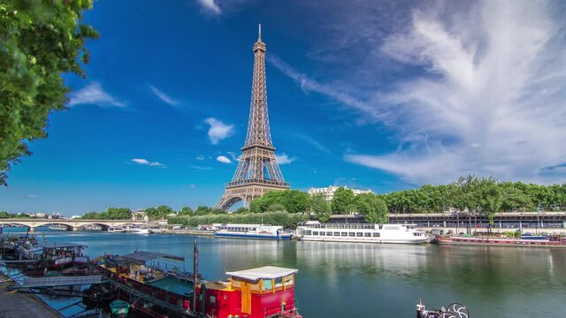 The Eiffel tower timelapse hyperlapse from waterfront at the river Seine in Paris. Ship and boats on river at sunny summer day