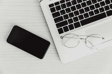 laptop computer on the desk with smartphone and glasses top view monotone for minimal business flat...