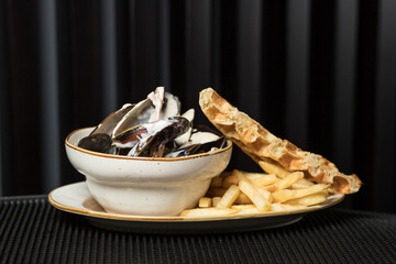 Mussels in copper cooking dish with french fries and waffle