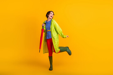 Full length photo portrait of excited girl with umbrella on one leg isolated on bright yellow...