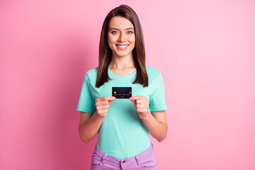 Photo portrait of woman holding credit card with two hands isolated on pastel pink colored background