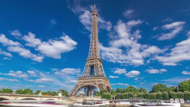The Eiffel tower timelapse hyperlapse from waterfront at the river Seine in Paris. Ship and boats on river at sunny summer day