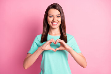 Photo portrait of romantic girl showing heart with fingers symbol of love in turquoise t-shirt isolated on pastel pink color background