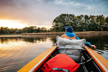 Fototapeta premium Evening kayak trip along the river in autumn. The active lifestyle of the child in the family.