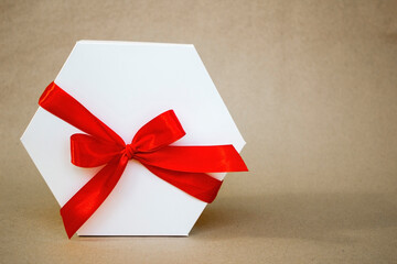 White gift present box with red ribbon on craft paper background and copy space
