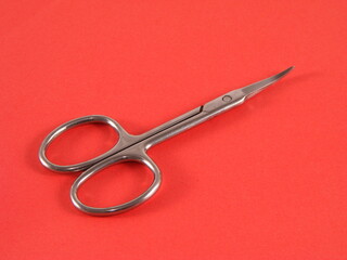 Manicure scissors isolated on red background
