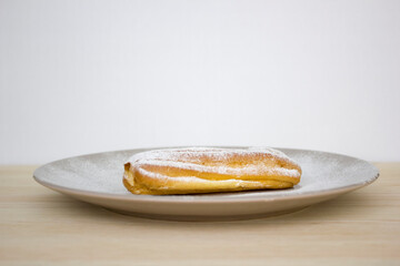French choux eclair, profiteroles on serving plate, dusted with powdered sugar/sprinkled with icing sugar.