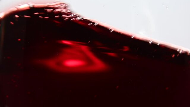 Close up swirling red wine in wineglass over white
