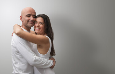 Attractive middle-aged Spanish couple showing love and happiness hugging.