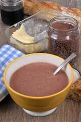 Bol de lait au chocolat avec un bocal de chocolat en poudre, du pain , un pot de miel et du beurre et une serviette de table en gros plan