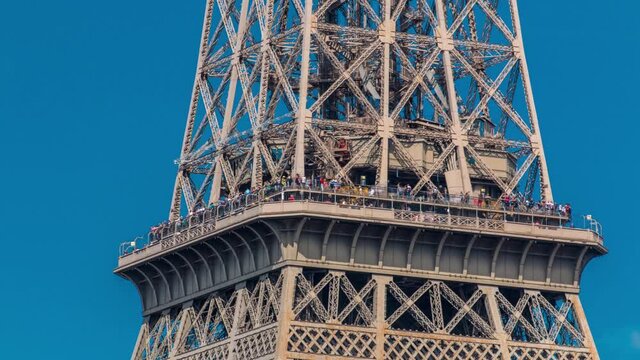 Close up view of middle section of the Eiffel Tower with tourists on observation deck timelapse in Paris, France. Sunny summer day with blue clody sky