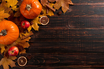 Orange pumpkins, fallen leaves, apples, nuts, spices and cones on a wooden background. The concept...