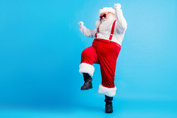 Full length photo of cool hipster fat santa claus dance x-mas christmas tradition discotheque wear suspenders overall sunglass boots isolated over blue color background