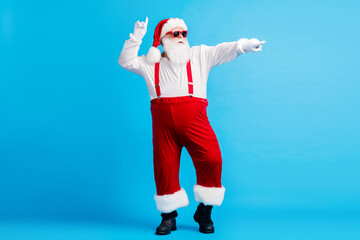 Full size photo of cool hipster santa claus with big belly dance x-mas christmas magic discotheque wear suspenders cap sunglass isolated over blue color background