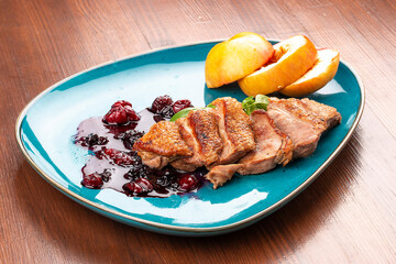 Magre duck breast with baked apple and berry sauce. On a decorative plate