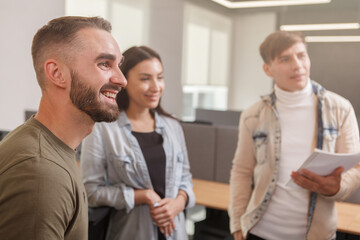 Obraz premium Handsome young businessman smiling, talking to his business team at the office