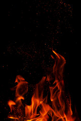 Fiery flame with sparks on a black background. Texture (element) for barbecue or cooking.