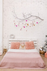 Stylish Christmas white badroom interior, bedroom with a lot of lights and  decorated white branch and pink fur pillows. Comfort home. Christmas decorated room in loft style