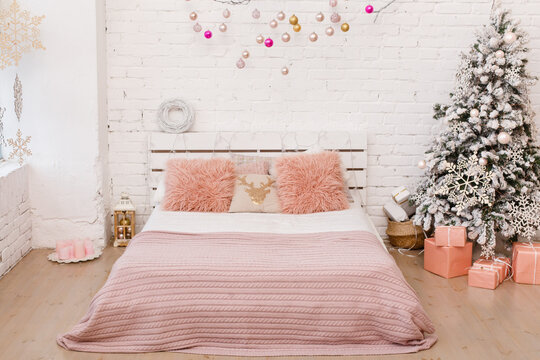 Stylish Christmas white badroom interior, bedroom with a lot of lights and  decorated white branch and pink fur pillows. Comfort home. Christmas decorated room in loft style