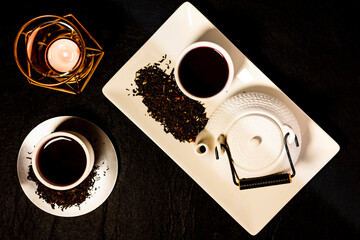 Tea set on dark background illuminated with dim light whit a candle