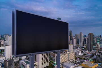 Blank black road billboard with Bangkok cityscape background at night time. Street advertising poster, mock up, 3D rendering. Side view. The concept of marketing communication to promote idea.