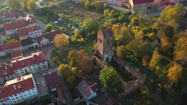 The restored facades of the Zheleznodorozhny town against the background of an abandoned old Prussian church, Russia, autumn time