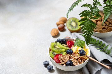 Breakfast with fresh Greek yogurt, strawberries, kiwi and granola on a light concrete background. Healthy food nutrition, snack or breakfast.