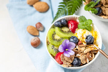 Breakfast with fresh Greek yogurt, strawberries, kiwi and granola on a light concrete background. Healthy food nutrition, snack or breakfast.