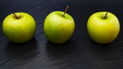 Three ripe fresh green apples isolated on black background. Free copy space. School snacks or organic food concept
