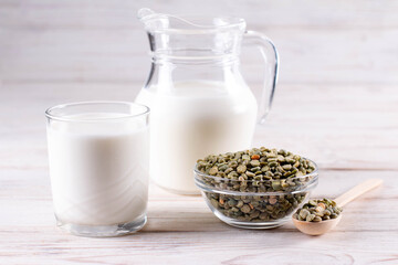 Vegetable pea milk in a bottle and peas in a jar on a white table. Gluten free, lactose free product