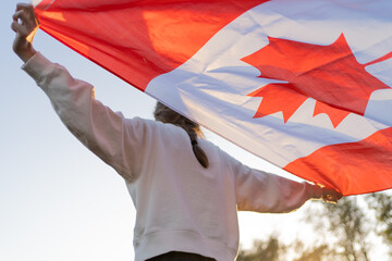 The flag of Canada in the hands of a person. Canadian symbol against the backdrop of a beautiful...