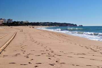 View of Sandy Beach with Footprints & Tracks against Blue sky 