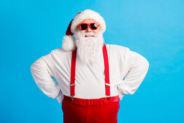 Fototapeta na wymiar Photo of funky santa claus with big belly put hands x-mas christmas tradition spirit creature wear headwear cap sunglass overalls isolated over blue pastel color background