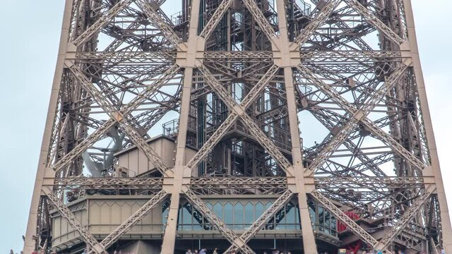 Close up view of first section of the Eiffel Tower with tourists on observation deck timelapse in Paris, France. Sunny summer day with blue clody sky