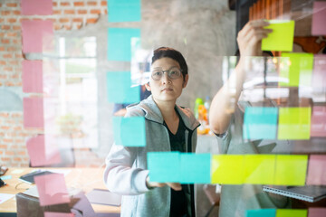 Asian business woman leader and  team  wearing casual outfit meeting  with business partner using note paper for present idea.Agile and scrum meeting