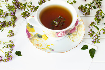floral tea in a cup on a white background close-up. background with flowers oregano and a cup of tea with a shower.