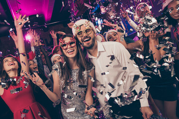 Photo of cheerful funky people man girl look camera catch falling sequins enjoy dance floor modern club indoors