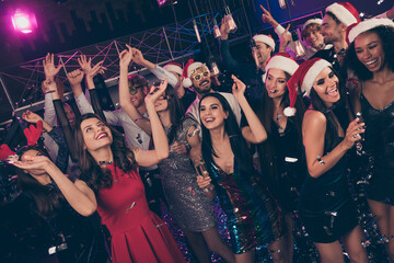 Photo of funny crazy people new year gathering enjoy raise palms hold glass x-mas headwear modern club indoors
