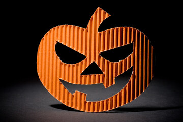 Studio photo of cut out orange paper halloween pumpkin on a black background. Spotlight on subject.