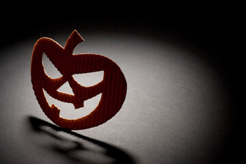 Studio photo of cut out orange paper halloween pumpkin on a black background. Spotlight on subject.