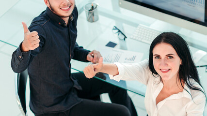 top view. two employees sitting at the Desk and showing thumbs